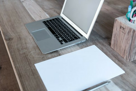 Öppen MacBook och papper på ett bord.