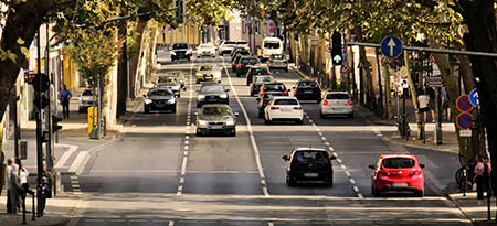 Bilar kör i båda riktningar på fyrfilig väg i stadsmiljö.