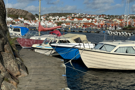 Båtar ligger förtöjda vid bryggan utmed berget på St Görans ö.