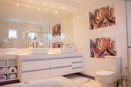 Vitt badrum med toalett, handfat och stora speglar.