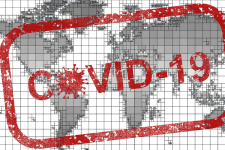 En röd stämpel med texten Covid-19 är stämplad rakt över en grå världskarta.