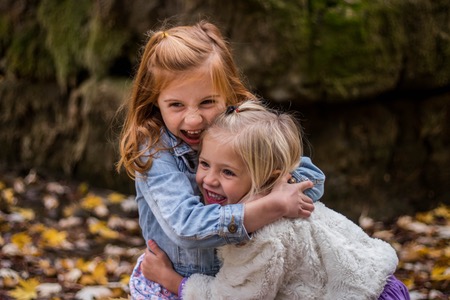 Två små flickor som kramas utomhus.