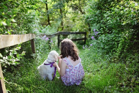 Flicka och hund i grönområde.